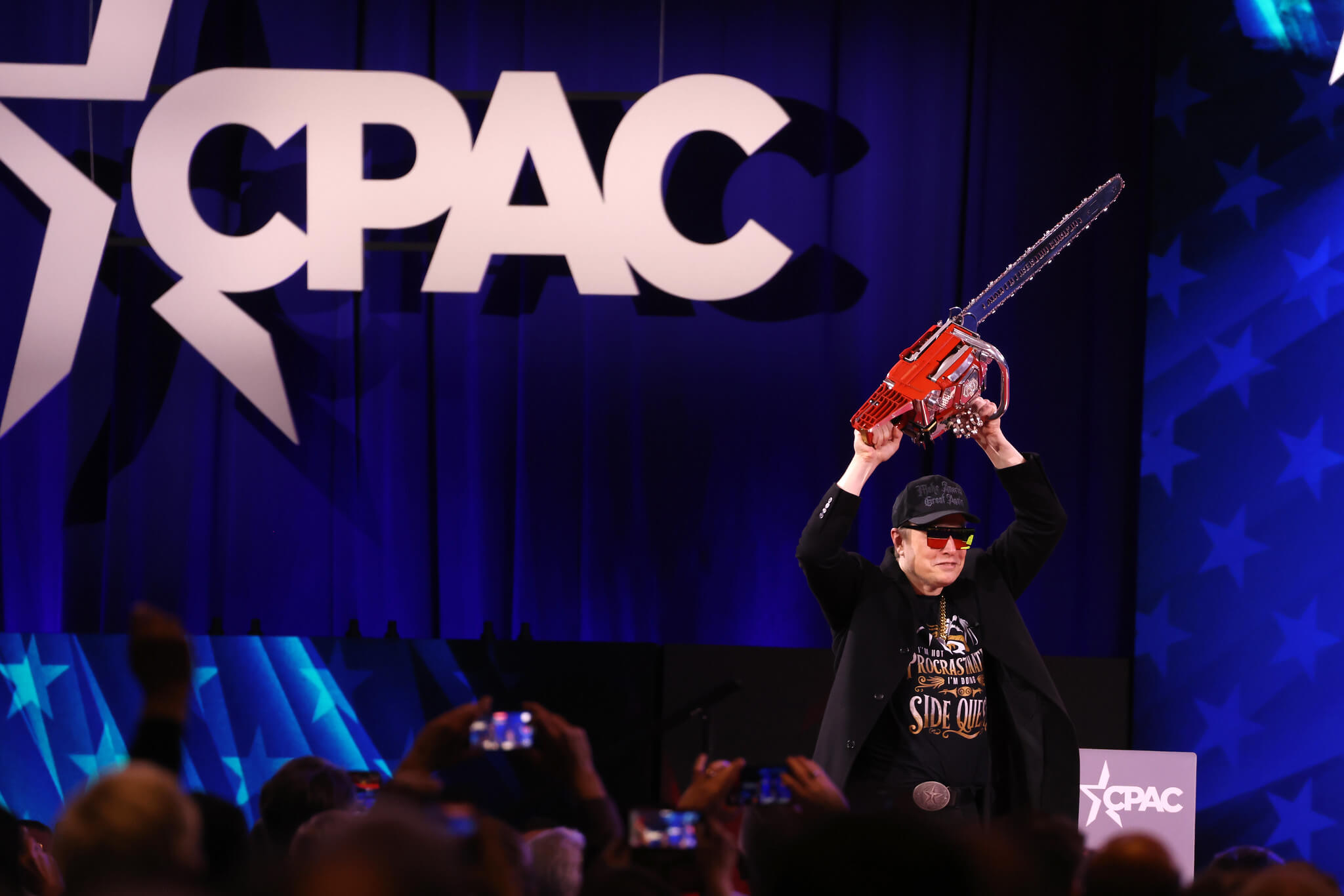 Elon Musk with a chainsaw on stage while speaking at the 2025 Conservative Political Action Conference in National Harbor, Maryland.