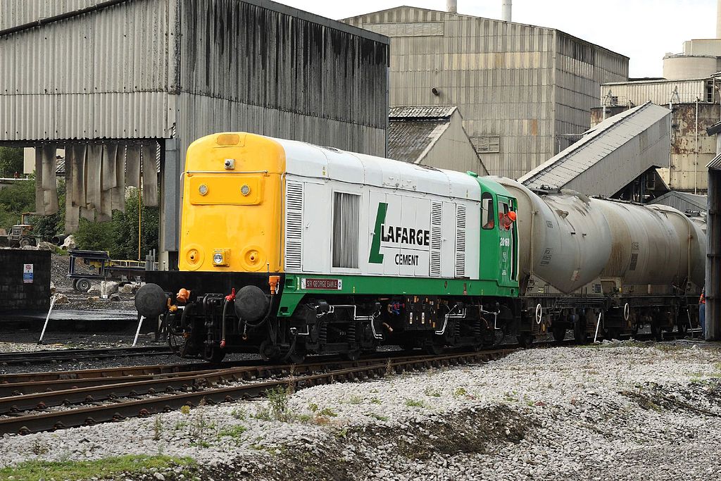 A transport with the Lafarge logo travels on train tracks.