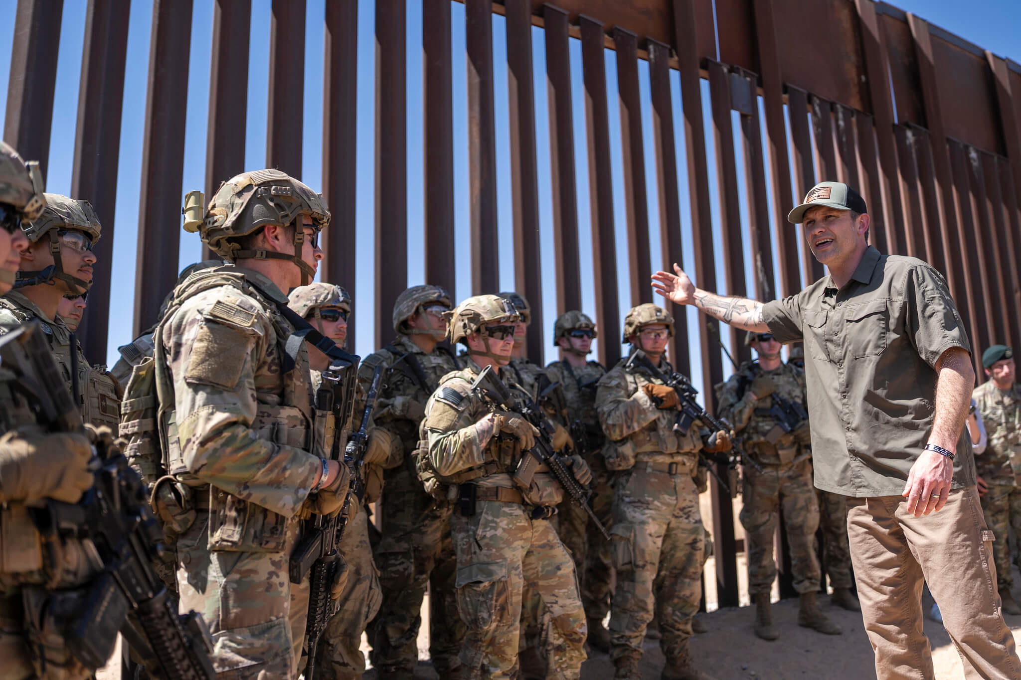 Secretary of Defense Pete Hegseth gestures at troops while and border fence while visiting the New Mexico National Defense Area